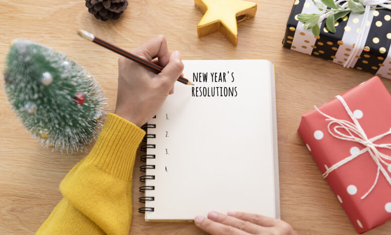 Woman hand writing New year's resolution on note paper in new year